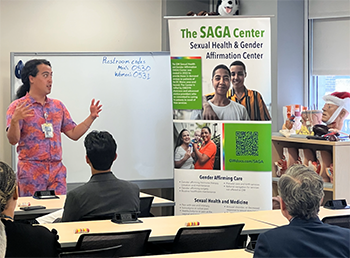 Someone talking about the SAGA Center to a group of people with a SAGA Center banner 
